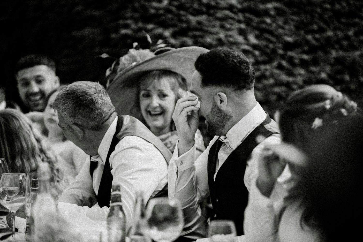 Black and white candid of guests laughing during a joyous wedding reception. Saltmarshe Hall