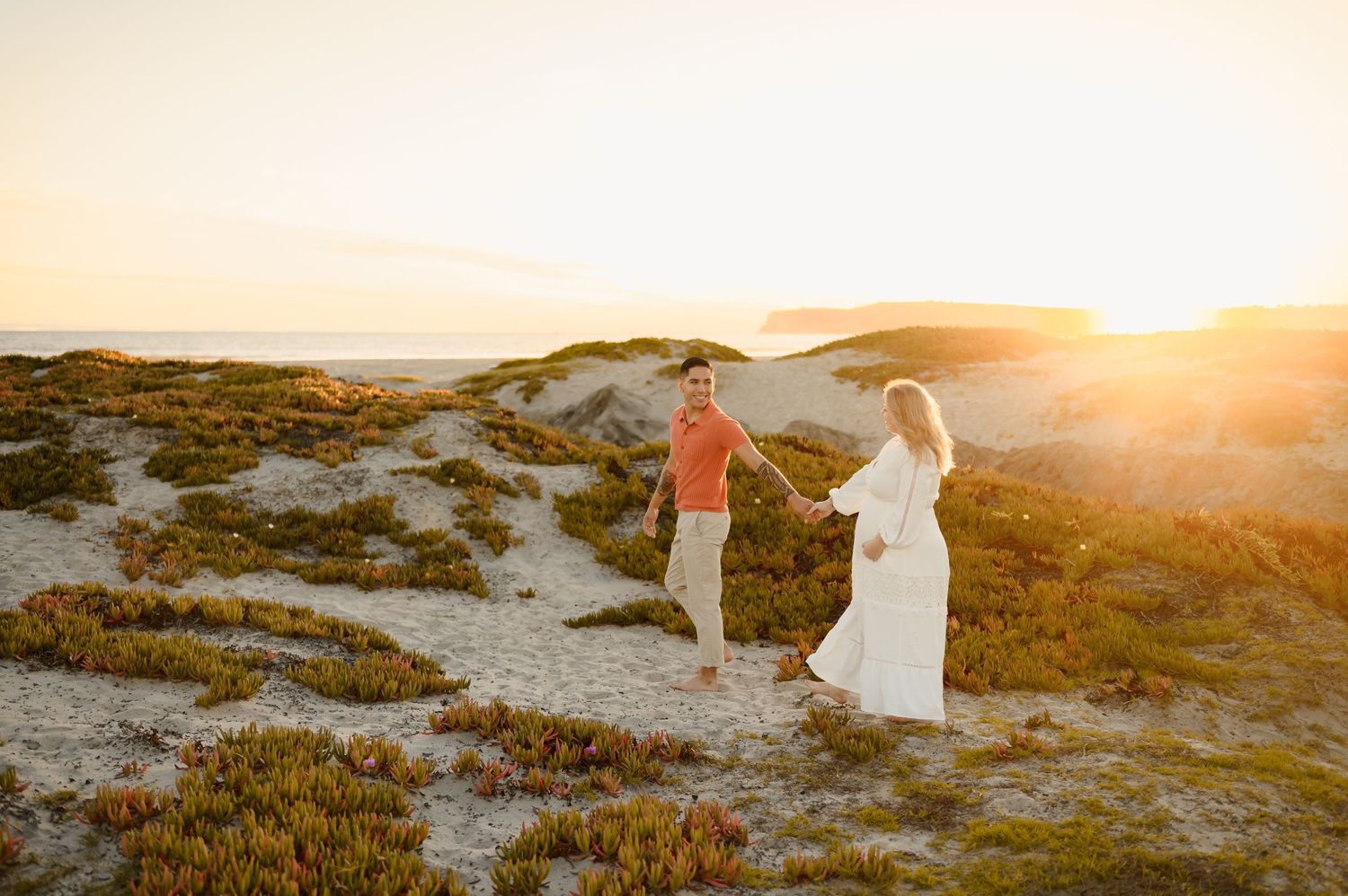 couple walking along sand dunes maternity photoshoot in Zachari Dunes, by Ventura maternity photographer