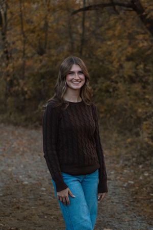 a girl standing in the woods during the fall season