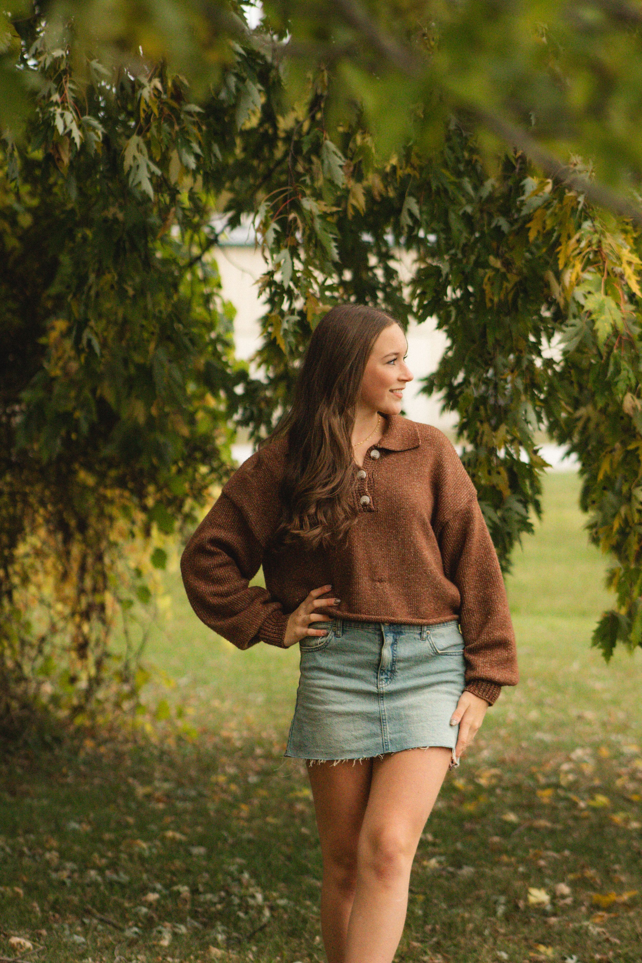 a girl posing inside a tree with hanging branches