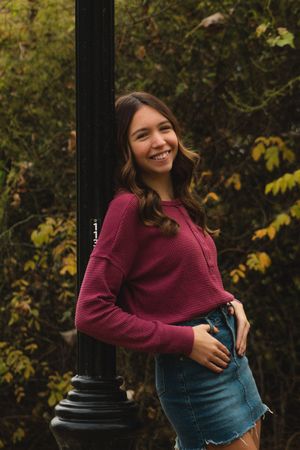 a girl leaning against a lightpole