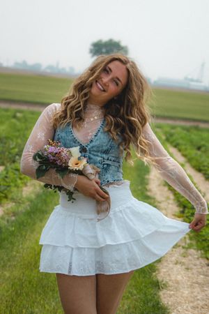 a girl cradling a bouquet of pink and purple flowers