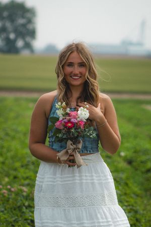 a girl feeling the wind with a bouquet of pink and purple flowers