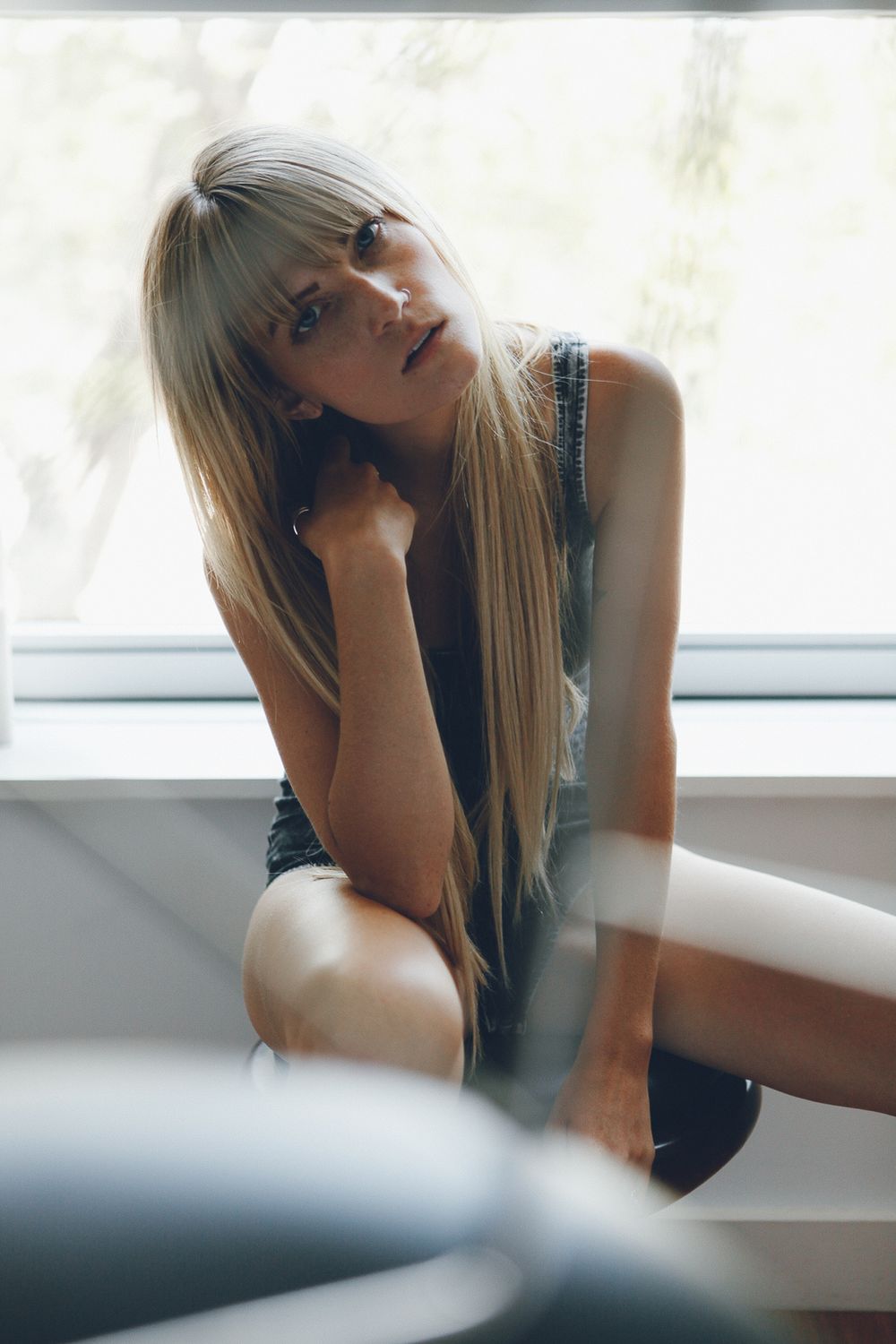 Indoor portrait with soft lighting and long straight blonde hair.