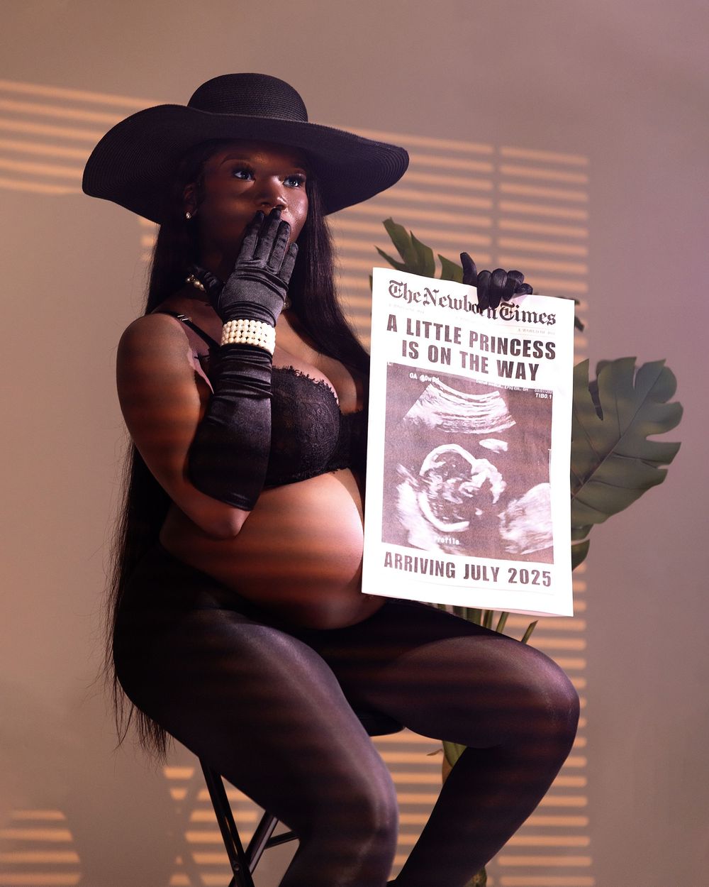 Pregnant woman in black outfit holds ultrasound newspaper announcing baby girl arriving July 2025.