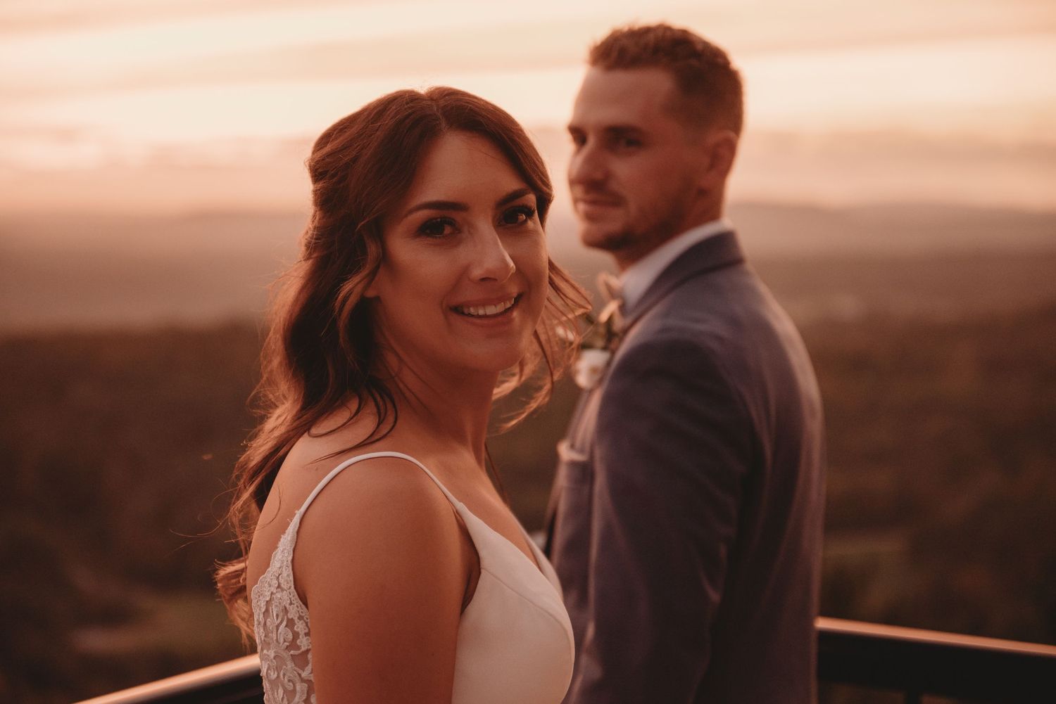 Romantic sunset portrait of newlyweds against a warm glowing sky.