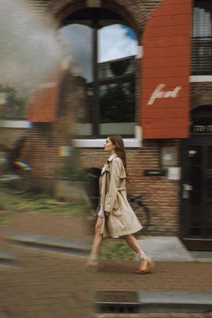 Motion blur sequence of someone walking past brick buildings in urban setting.