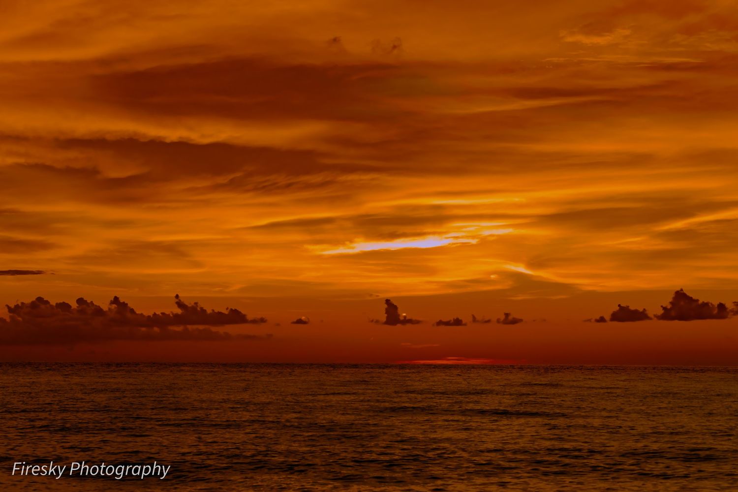 Dramatic sky with scattered clouds stretching over a vast desert landscape during sunset.