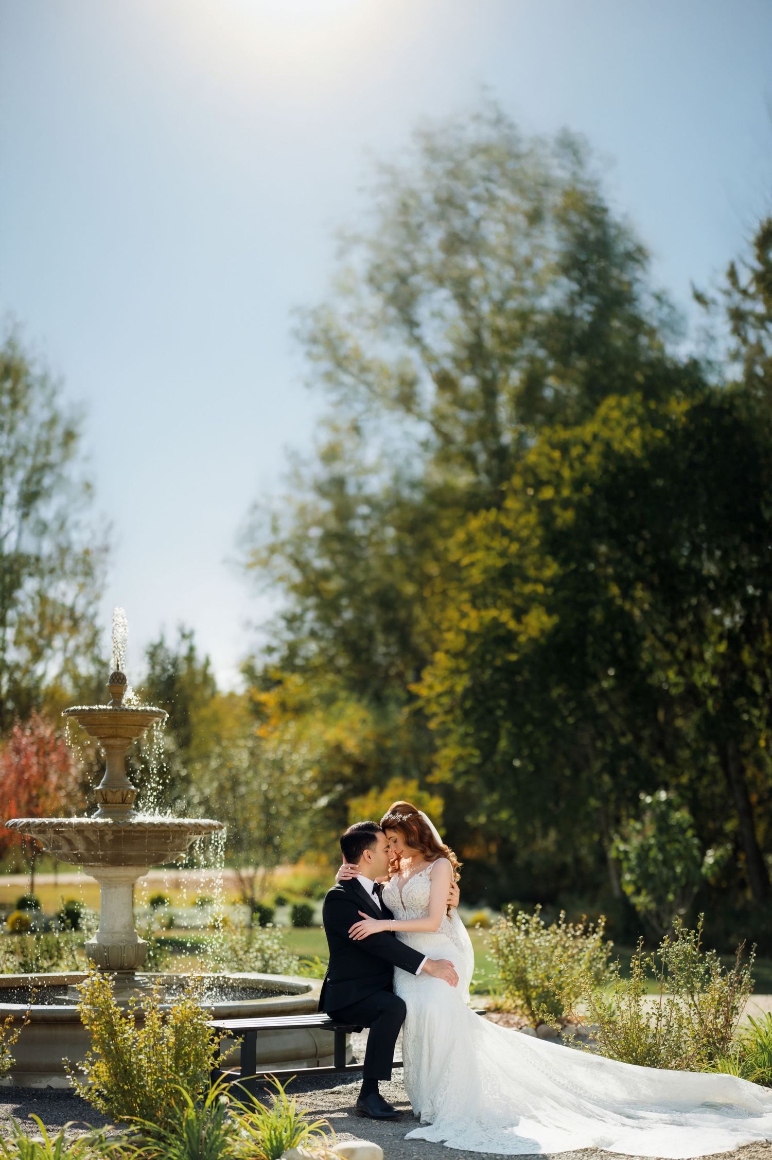Close-up side view of newlyweds sharing an intimate moment with bride wearing long wavy hair and lace wedding gown.