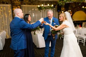 People in formal attire toasting with drinks at an elegant wedding reception venue. Ottawa Wedding Photographer
