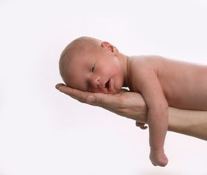 A sleeping newborn baby rests peacefully on outstretched hands.