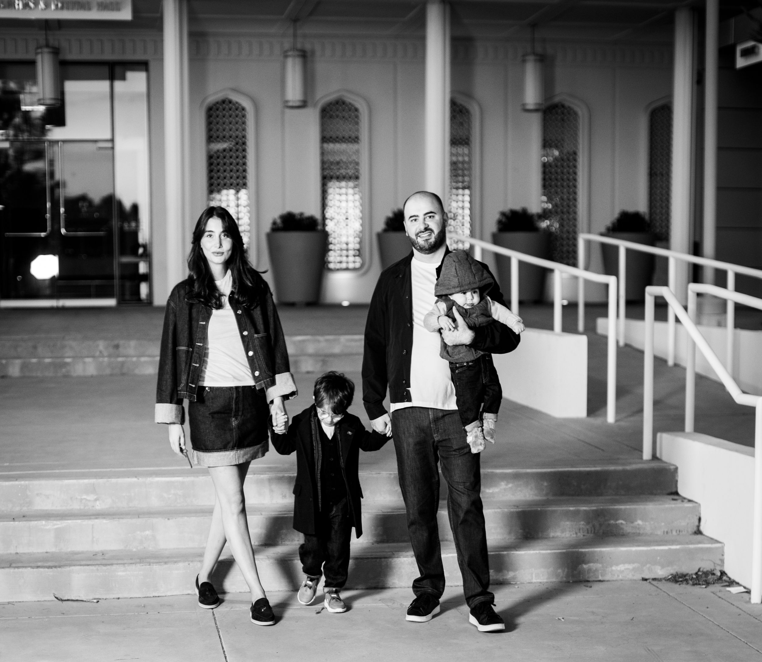 Black and white candid photo of family standing on building steps.