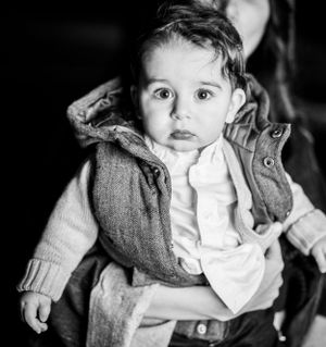 Black and white portrait of toddler wearing hooded vest and white shirt.