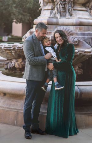 A family shares an intimate moment by a decorative stone fountain.