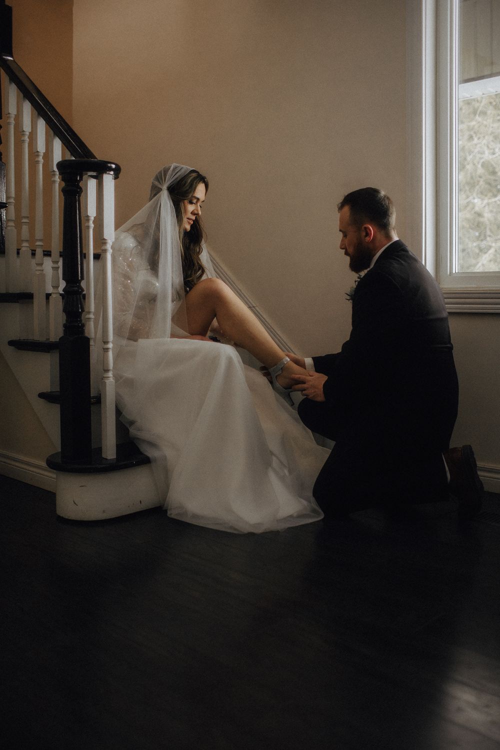 Artistic silhouettes of couple in wedding attire sitting on dark floor.