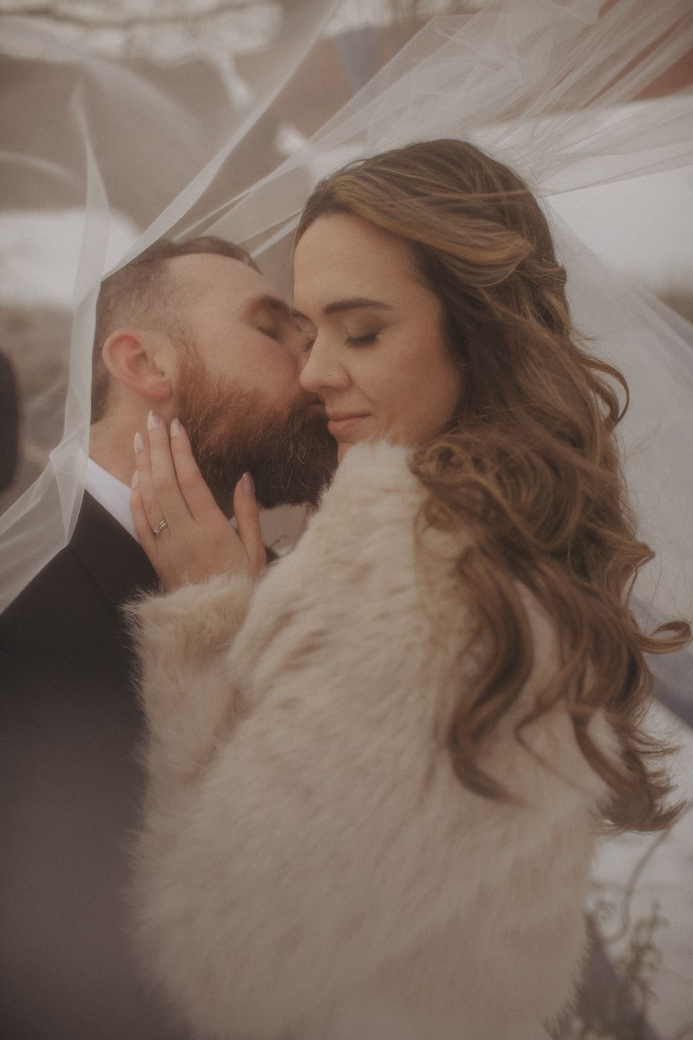 Intimate winter wedding portrait with couple in white fur wrap.