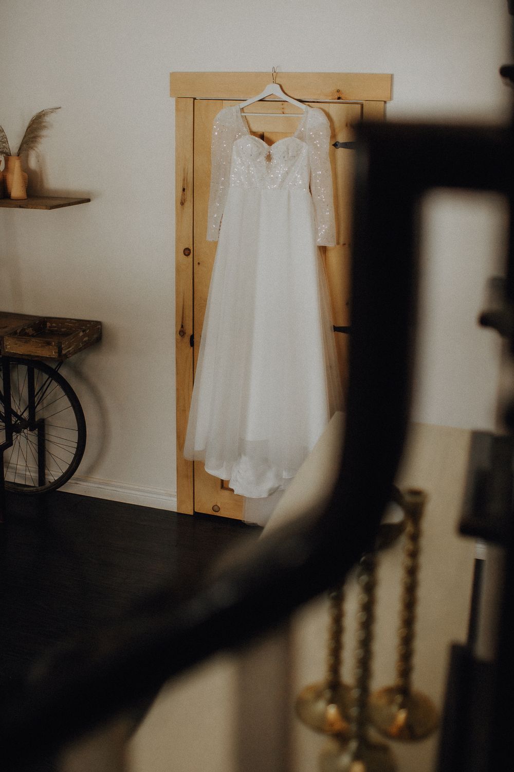White wedding dress hanging on wooden furniture in soft natural light.