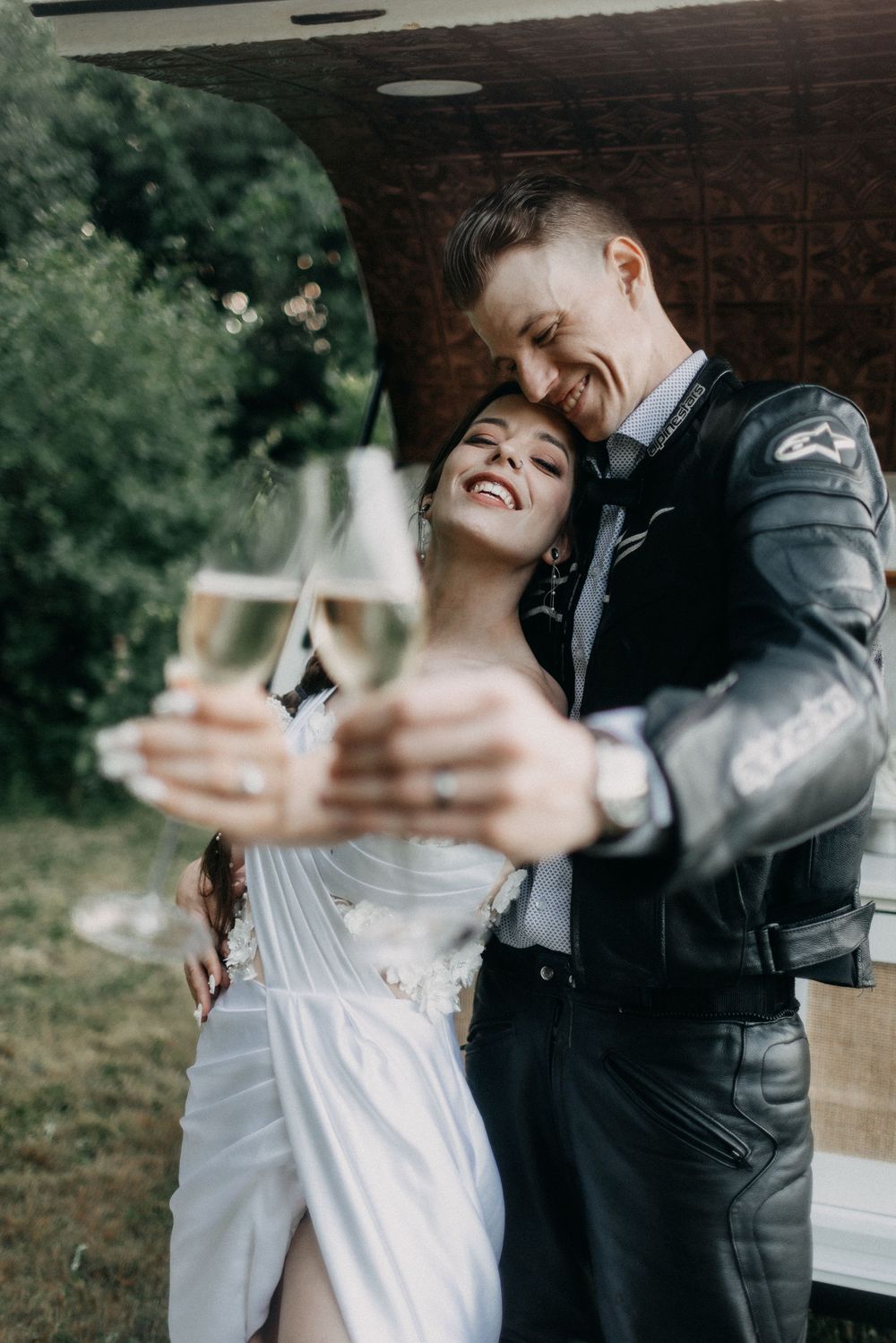 Romantic champagne toast between newlyweds at outdoor wedding reception.