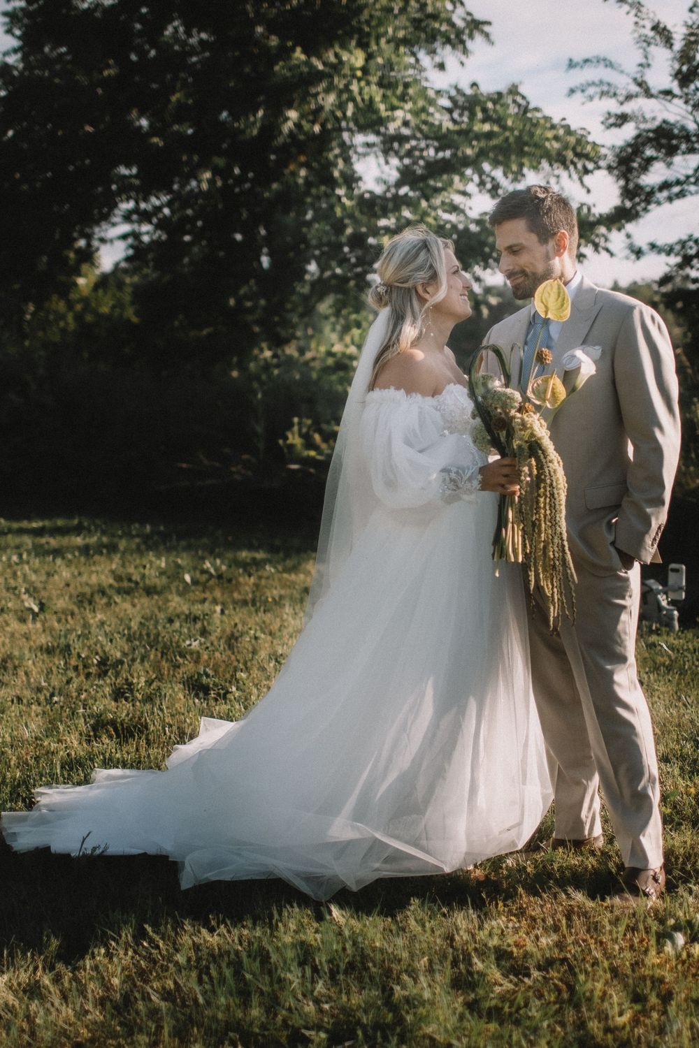 A romantic wedding photoshoot in a sunlit meadow with flowing white dress.
