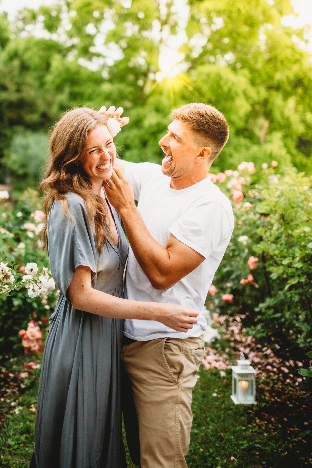A romantic moment captured in a lush garden setting with pink roses and natural sunlight.