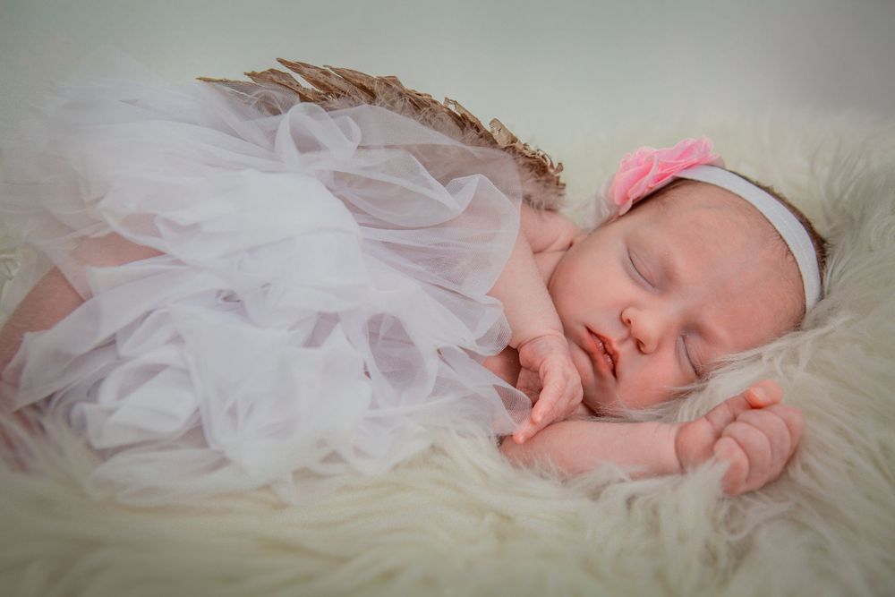 Peaceful sleeping newborn baby wrapped in soft white tulle fabric.