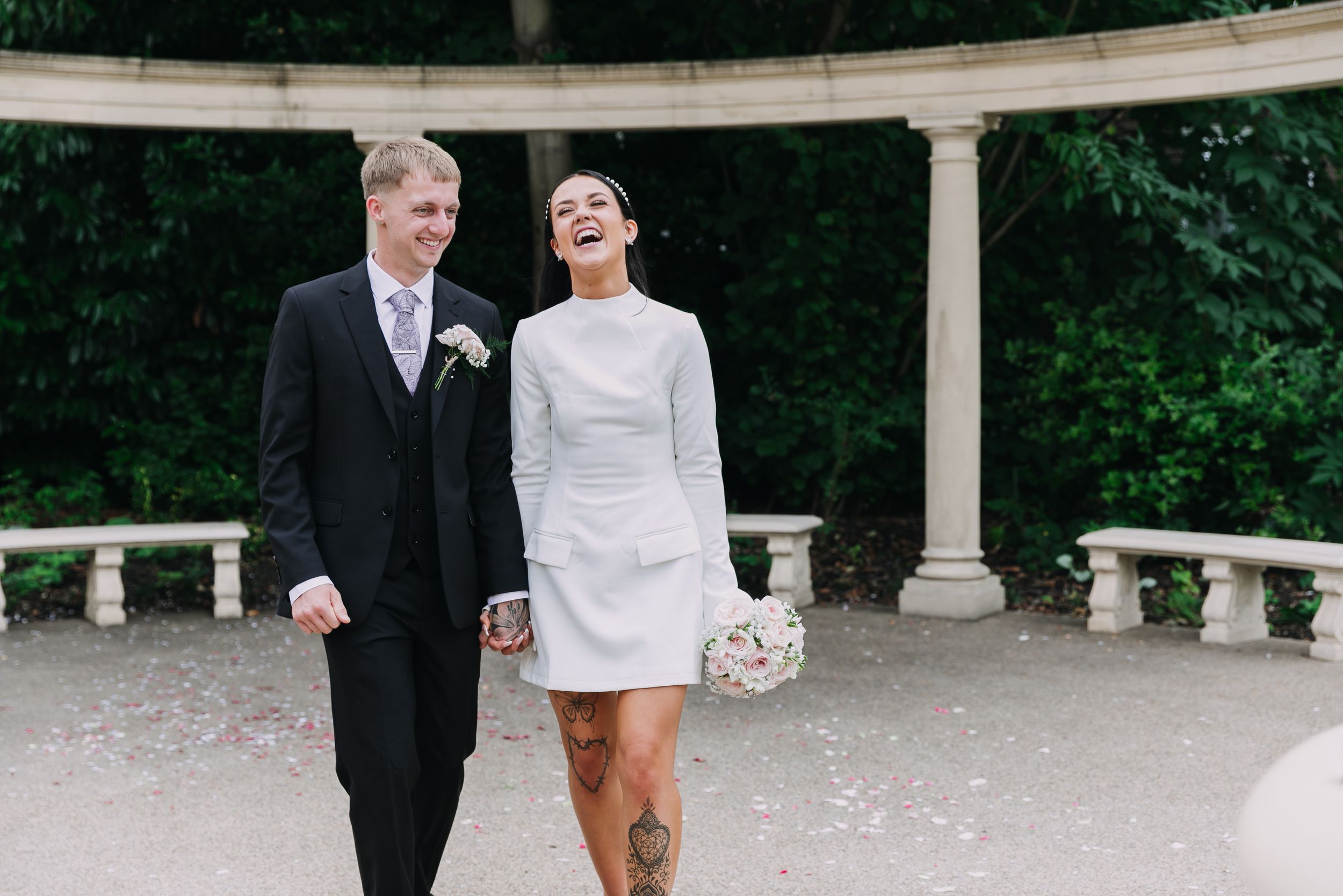 A couple poses in formal wedding attire in an elegant outdoor garden setting with stone columns. Photographer. Hull. East Yorkshire. Photo