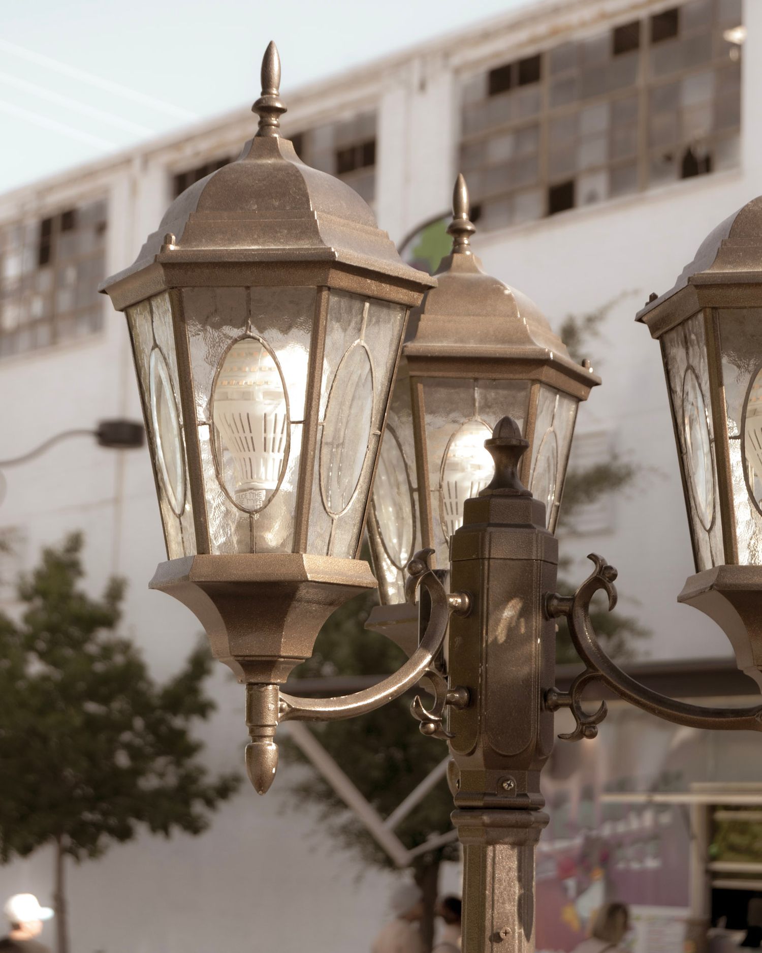 Vintage style outdoor lamp posts with ornate glass panels cast a warm glow against a blurred background.