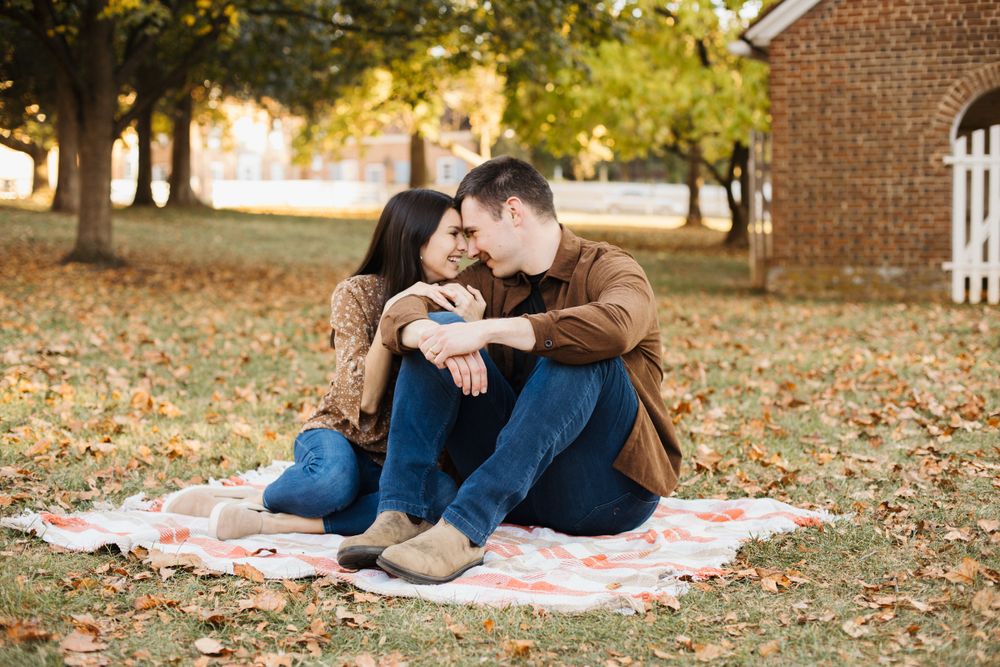 Couple lounges on picnic blanket during golden hour with autumn scenery.