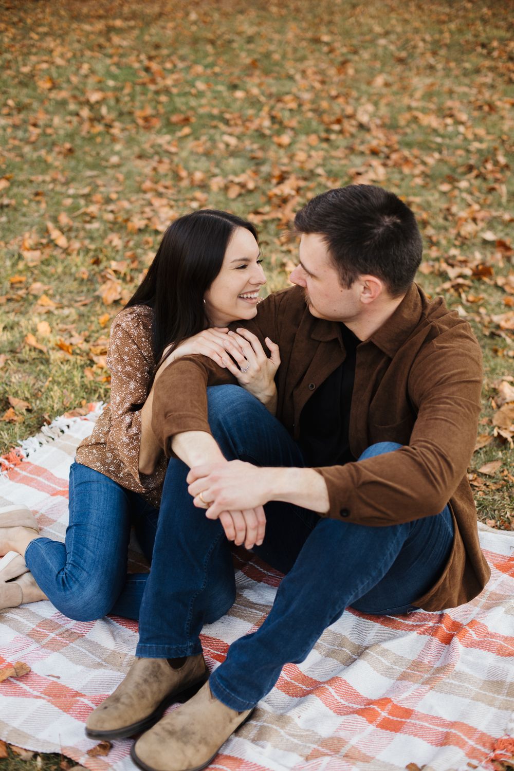 Intimate couple portraits on red and white blanket surrounded by autumn leaves.