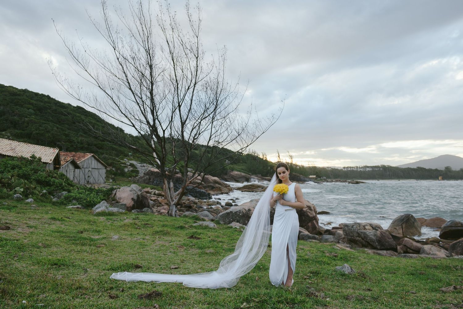 Coastal wedding photography with dramatic sky and rocky shoreline in the background.