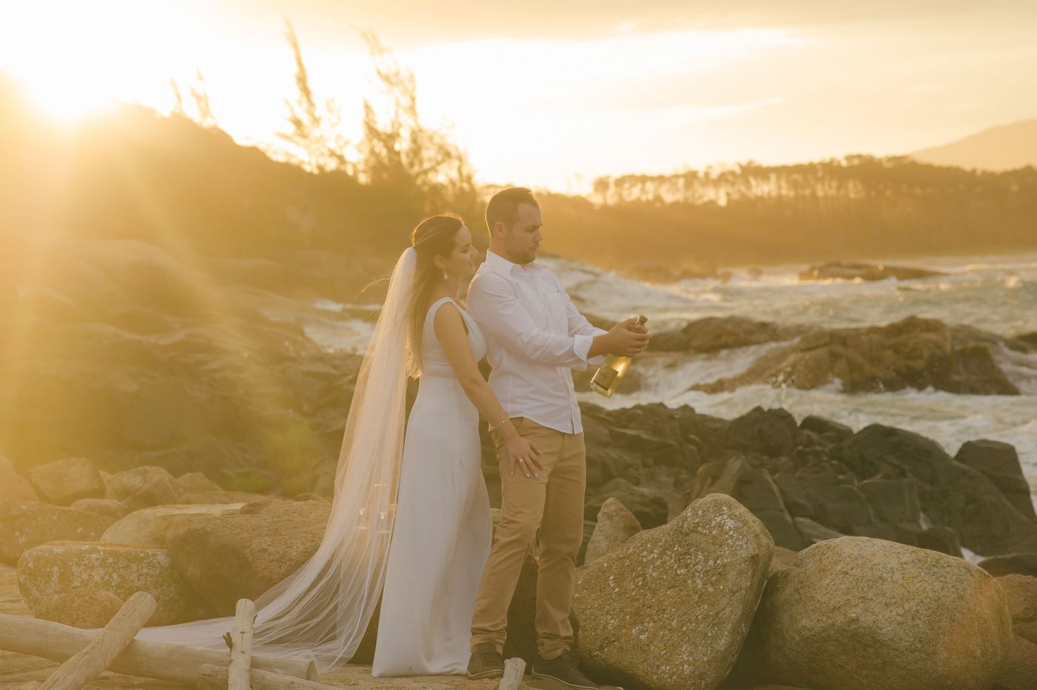 Golden hour coastal portrait with dramatic waves crashing on rocks in the background.