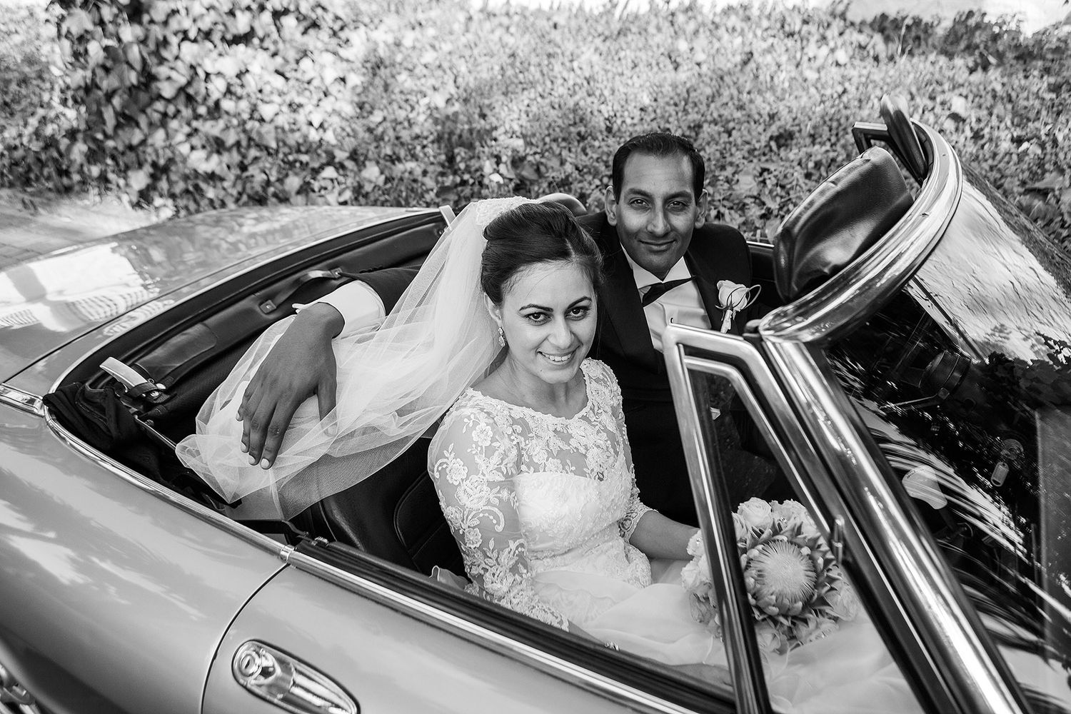 bridal couple in classic wedding car before leaving