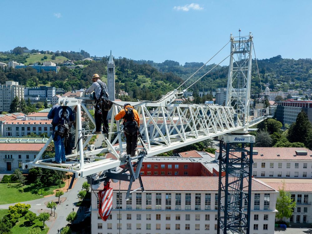 Milestone coverage of a specialized crew assembling a tower crane on an active university campus.