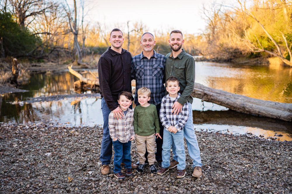 A group portrait taken by a creek with fallen trees in the background during autumn.