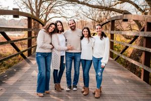 A casual group photo of five people posing together on a wooden bridge.