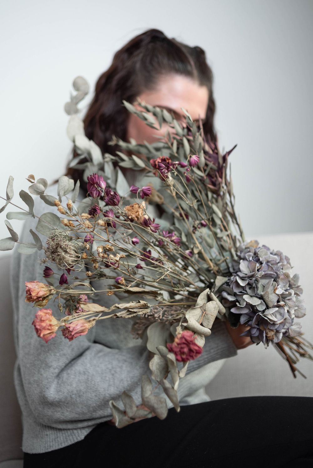 Creative portrait with dried flowers and botanicals creating artistic composition.