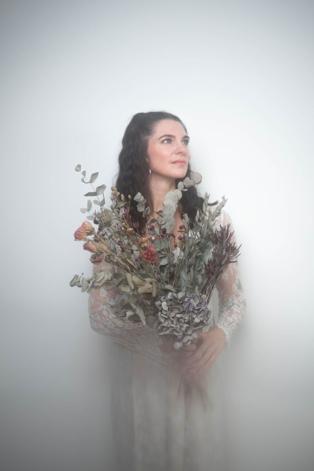 Atmospheric portrait surrounded by dried flowers and misty effects.