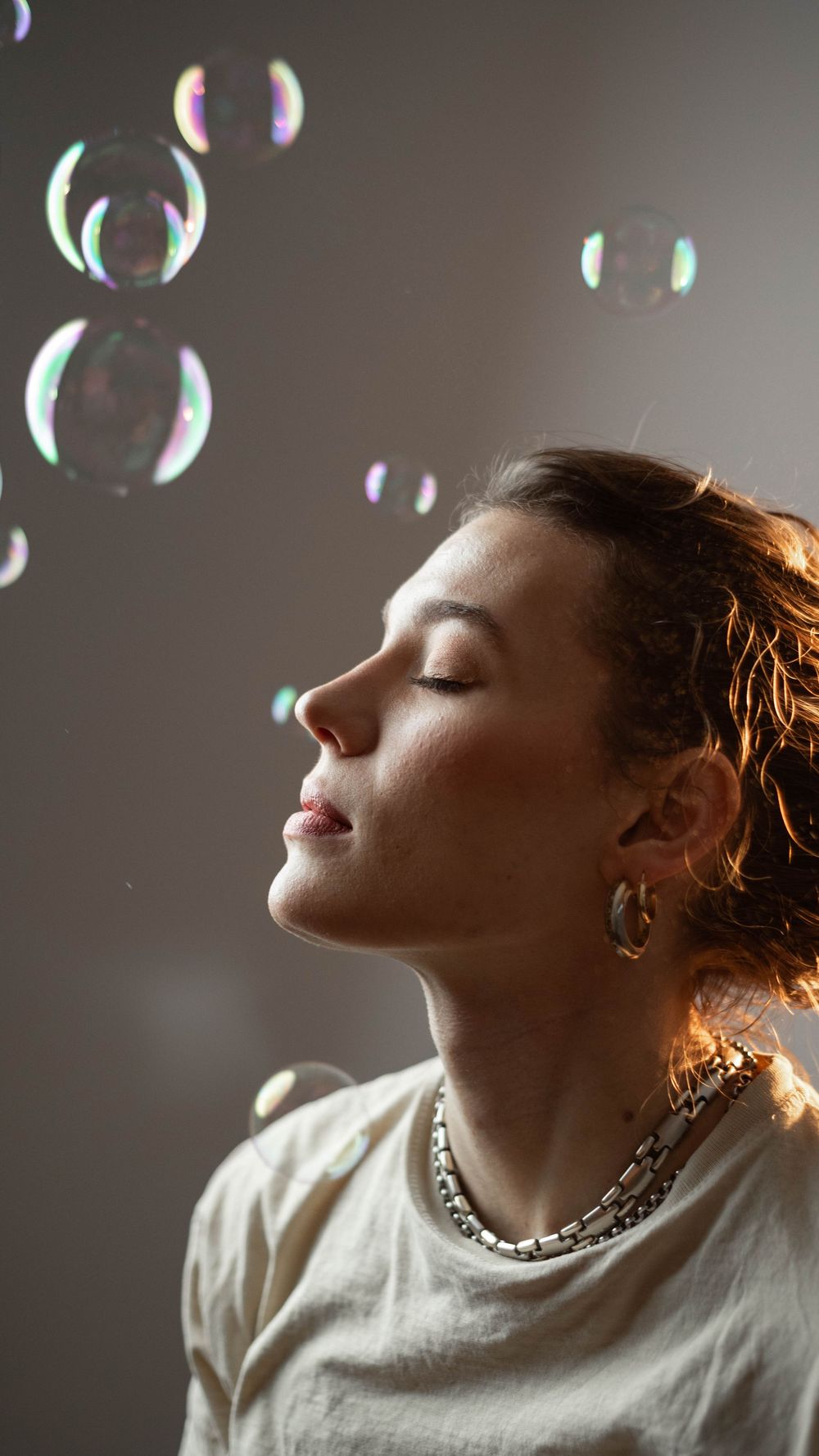 Artistic portrait with soap bubbles and dramatic side lighting creating dreamy atmosphere.