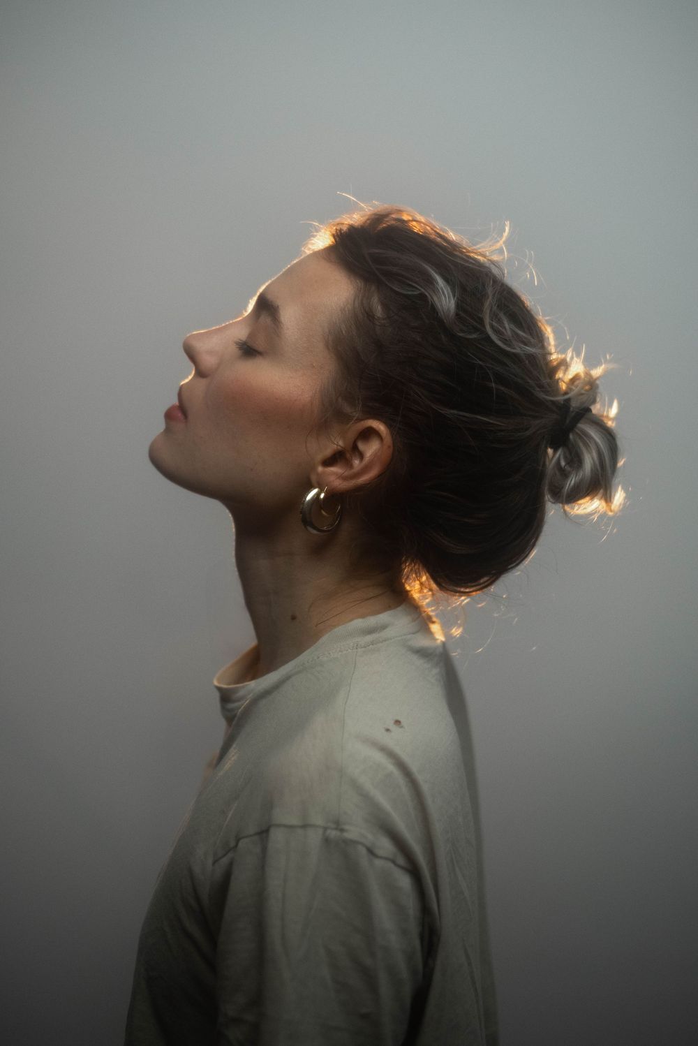 Artistic profile portrait series showing tilted head poses against a gray background in dramatic lighting.