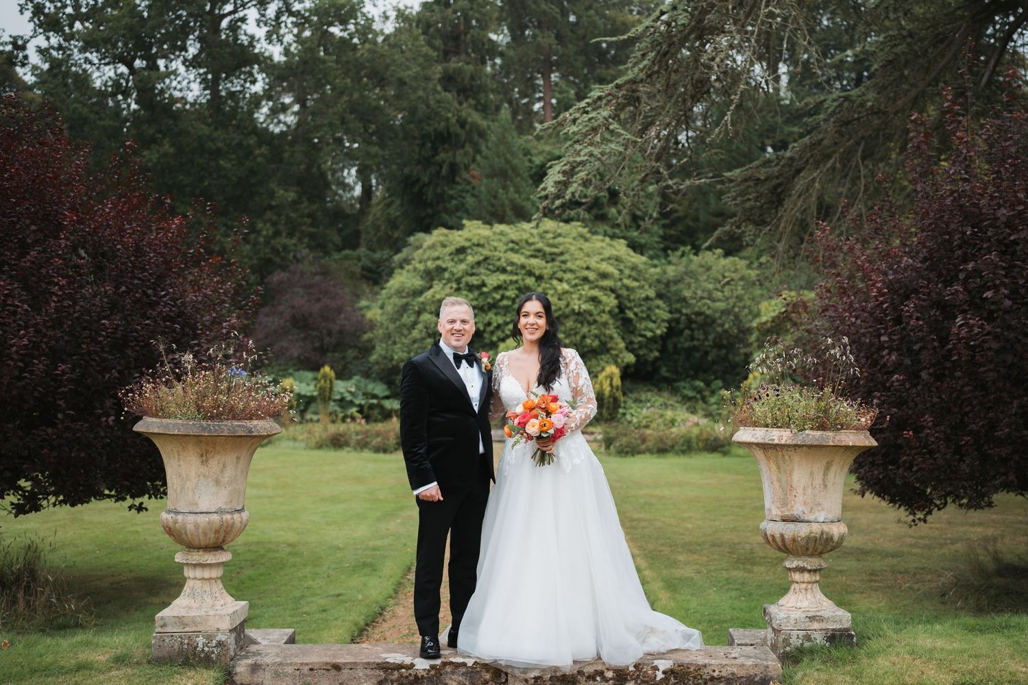 Couple walking together on garden path with groom wearing traditional Scottish kilt.