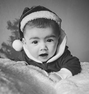 Black and white photo series of a baby lying on soft blankets showing different facial expressions and emotions.