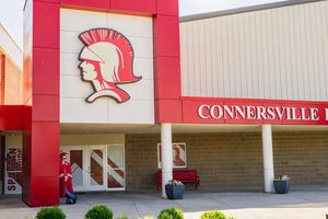 Red and white exterior of Connersville High School entrance with warrior mascot logo displayed prominently on the wall.