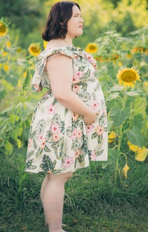 A little girl in a floral dress explores a vibrant sunflower field on a bright summer day.