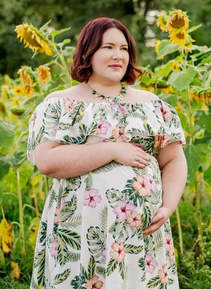 A floral print dress is displayed in a sunflower field on a summer day against a green nature backdrop.
