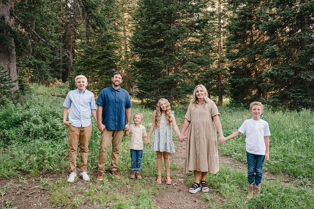 Family members lined up on a hiking trail with evergreen forest in the background.