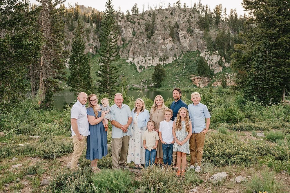 Large family group portrait with rocky mountain cliffs and forest landscape behind them.