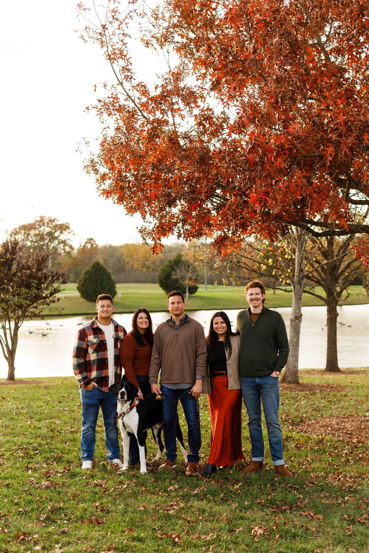 Group portrait under vibrant autumn trees next to a lake.