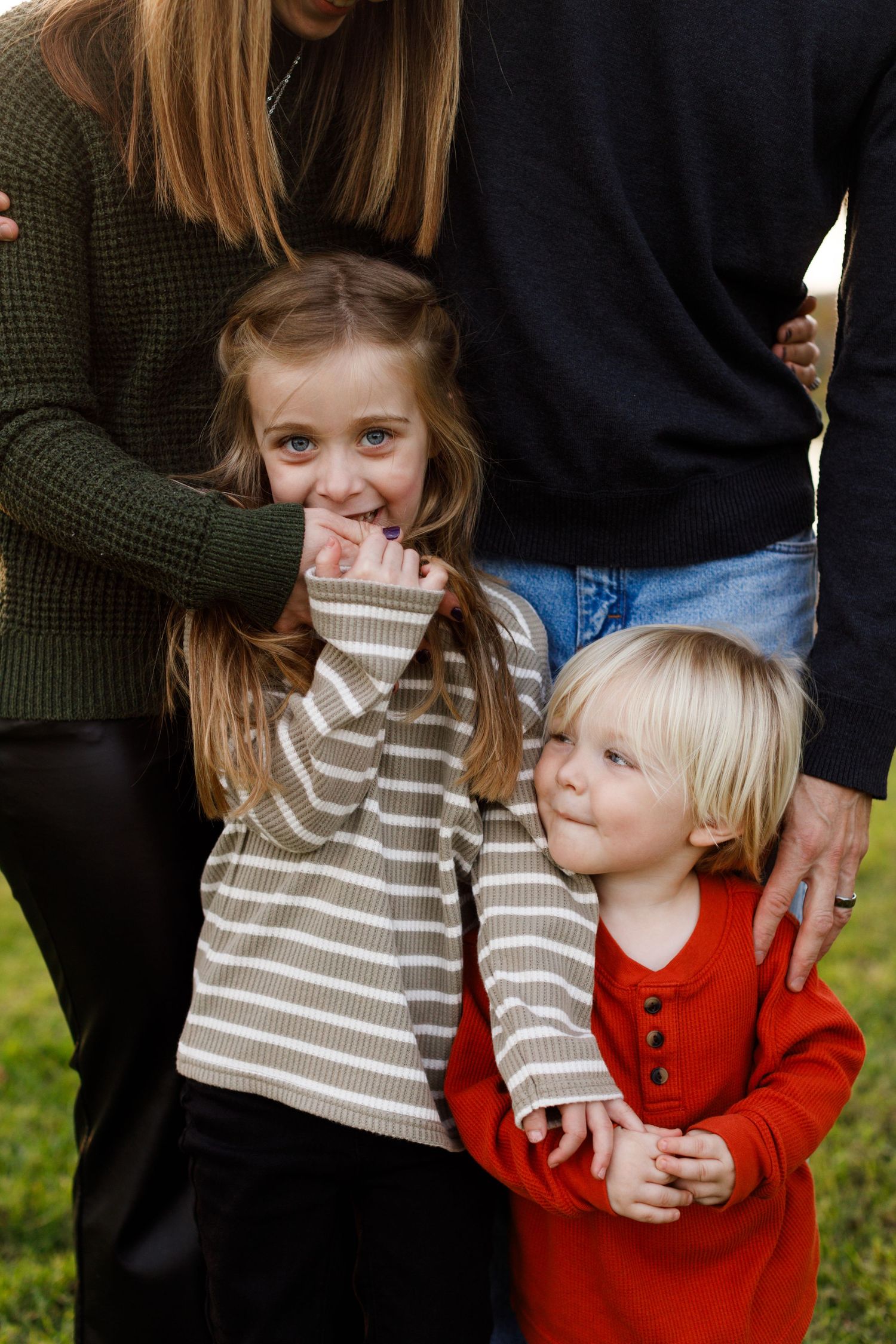 Two young children in sweaters standing close together outdoors.