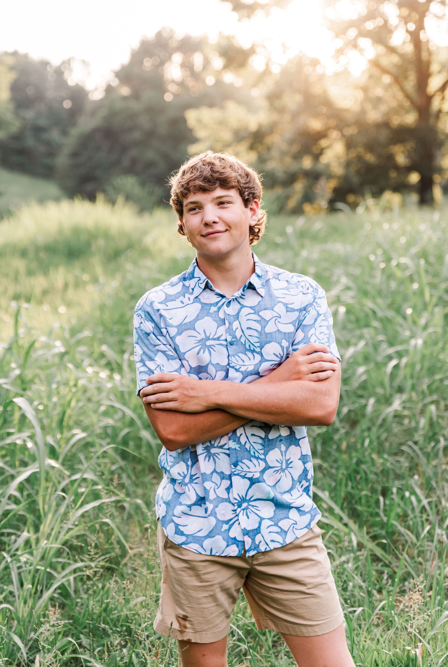Senior portraits of a boy smiling in a field at sunset in Kuttawa, Kentucky.