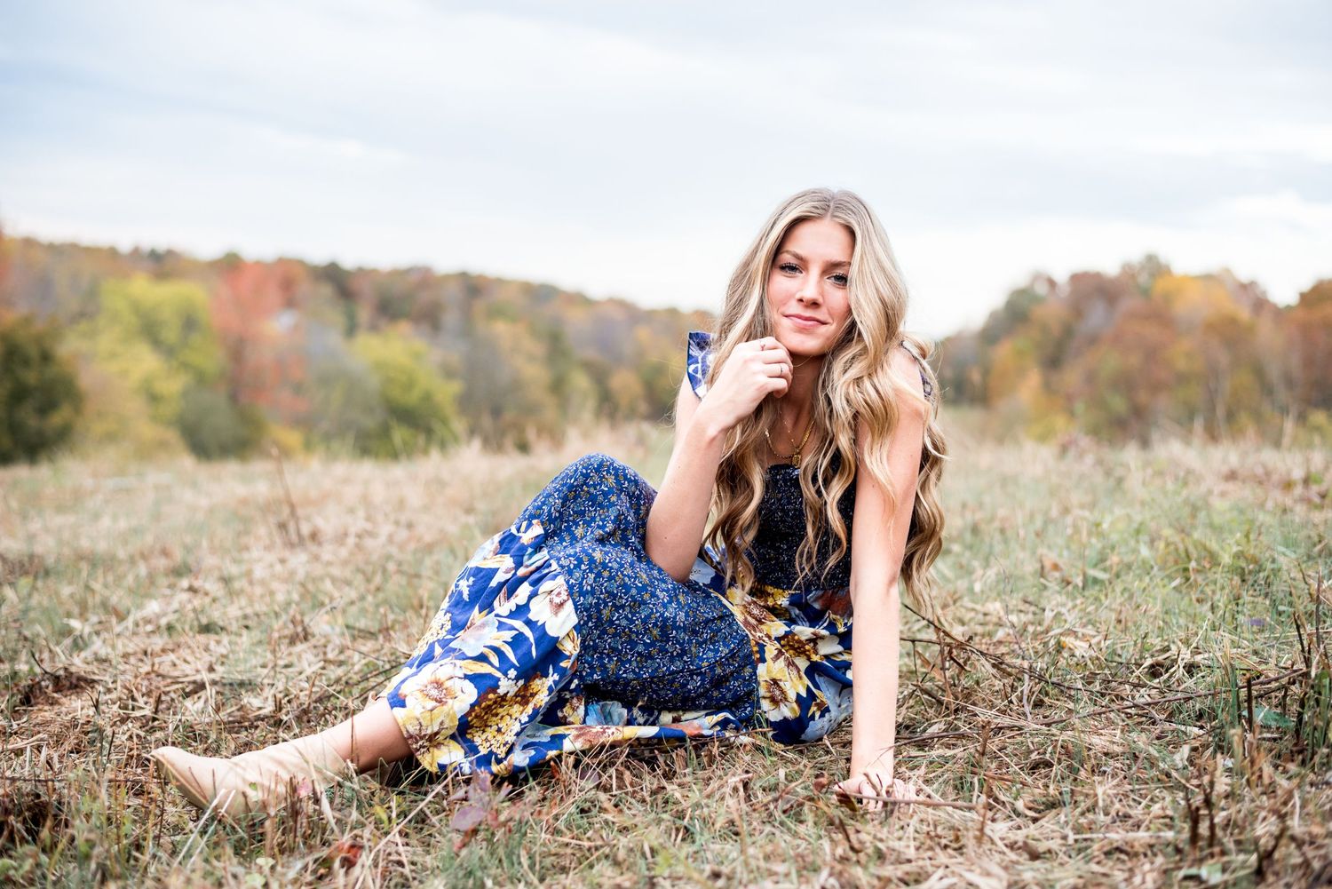 Senior girl wearing a long dress sitting in a field